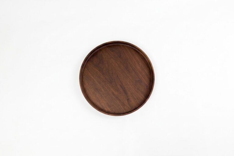 Round black walnut wood serving tray with raised edges and rich natural grain